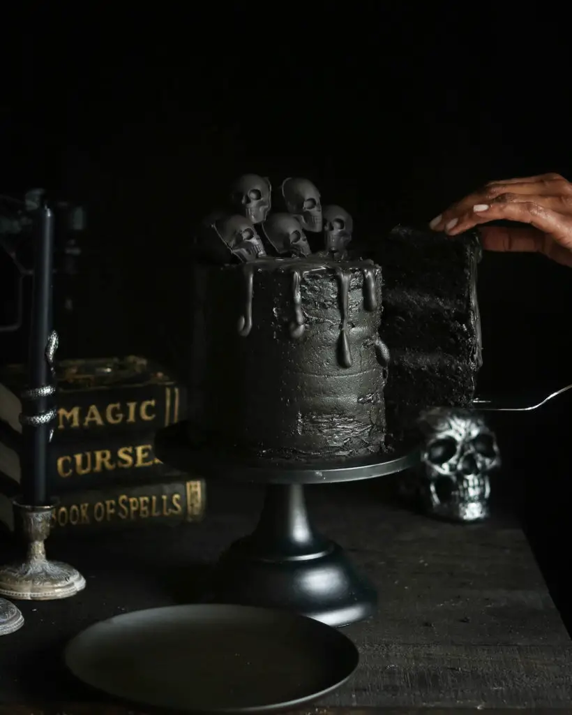 Removing a slice of Black Halloween Cake with skulls.