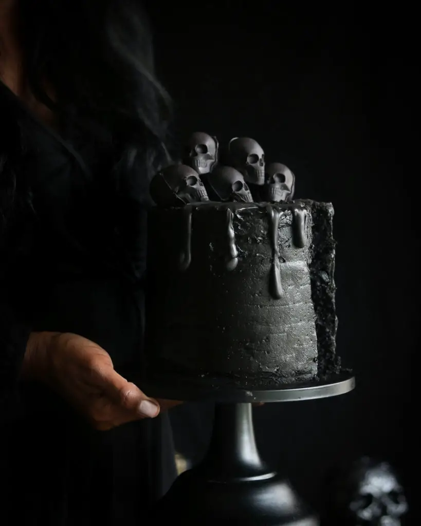 Holding a Black Halloween Cake with skulls.