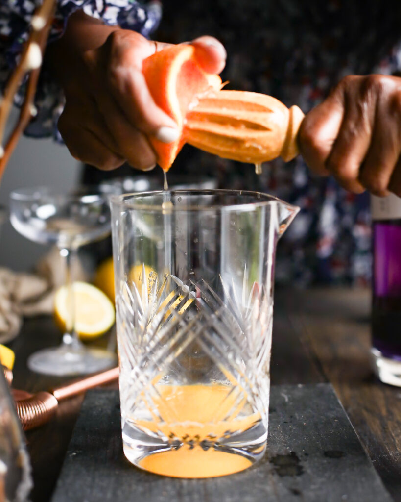 Squeezing orange juice into a cocktail glass.