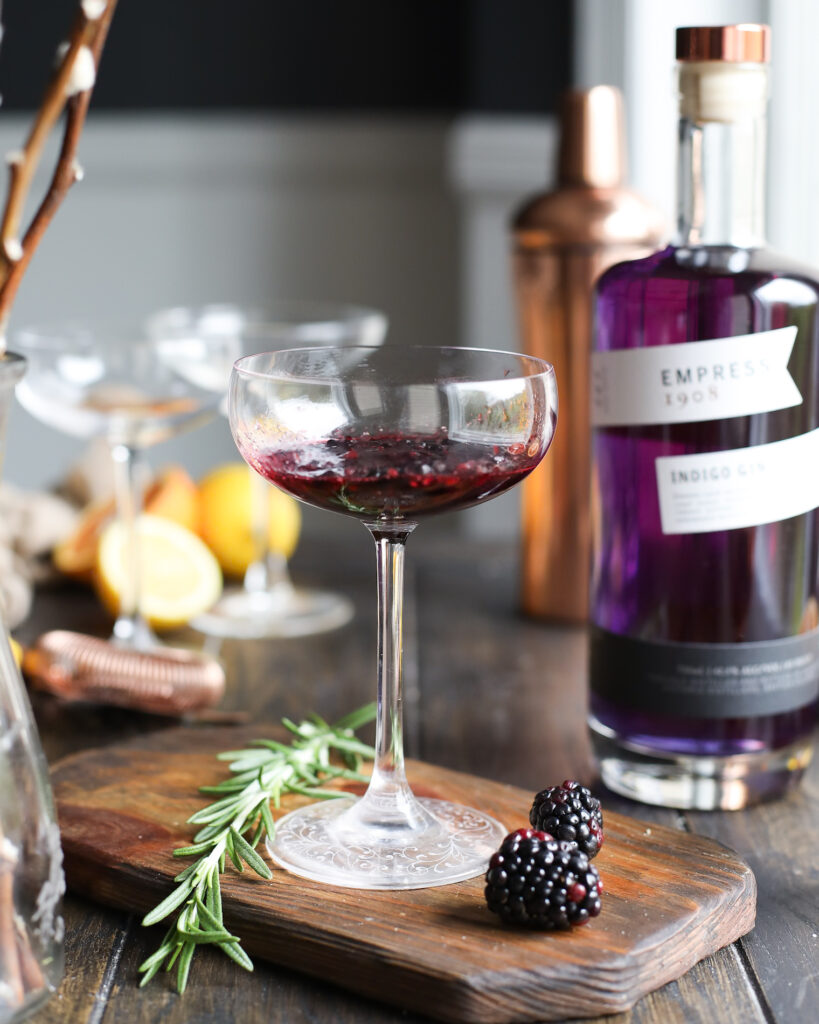 Coupe glass filled with muddled blackberries.